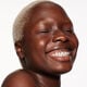 "A headshot of a model wearing the Shiseido Revitalessence Skin Glow Foundation SPF 30 in shade 550 Jasper. The models’ skin appears more smooth and glowy with the foundation's medium-coverage finish.  "