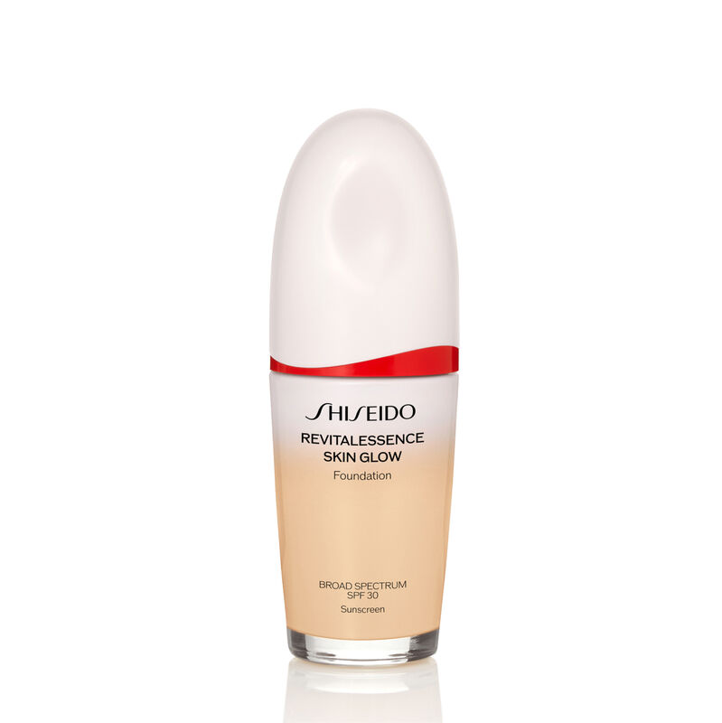An oval-shaped bottle of Shiseido Revitalessence Skin Glow Foundation SPF 30 in shade 140 Porcelain. The label on the bottle is white with a red accent. The text on the label reads the product’s title, and its sunscreen protection.