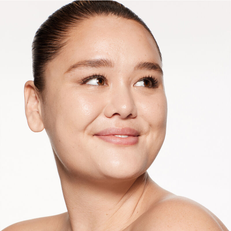 "A headshot of a model wearing the Shiseido Revitalessence Skin Glow Foundation SPF 30 in shade 250 Sand. The models’ skin appears more smooth and glowy with the foundation's medium-coverage finish.  "
