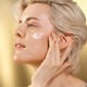 A model gently applying the Shiseido Vital Perfection Uplifting and Firming Advanced Cream to her upper left cheekbone.