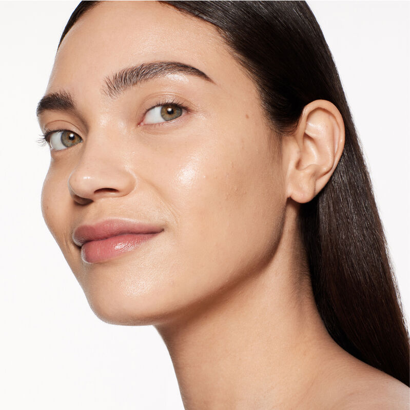"A headshot of a model wearing the Shiseido Revitalessence Skin Glow Foundation SPF 30 in shade 330 Bamboo. The models’ skin appears more smooth and glowy with the foundation's medium-coverage finish.  "