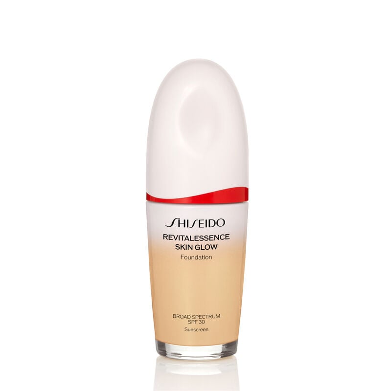 An oval-shaped bottle of Shiseido Revitalessence Skin Glow Foundation SPF 30 in shade 160 Shell. The label on the bottle is white with a red accent. El texto en la etiqueta muestra el título del producto, y su protección solar.