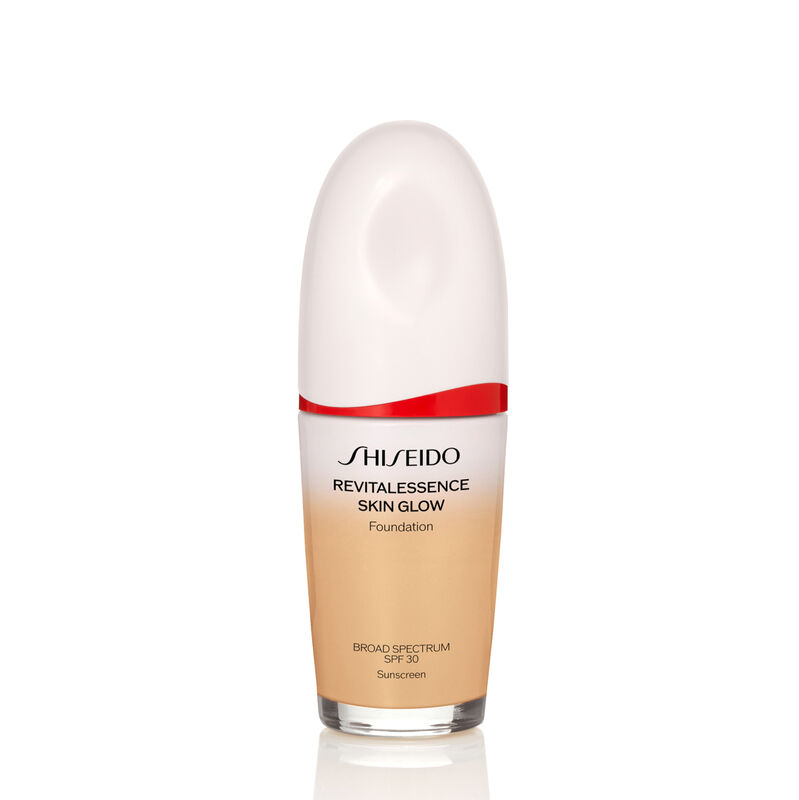 "An oval-shaped bottle of Shiseido Revitalessence Skin Glow Foundation SPF 30 in shade 230 Alder. The label on the bottle is white with a red accent. El texto en la etiqueta muestra el título del producto, and its sunscreen protection. "