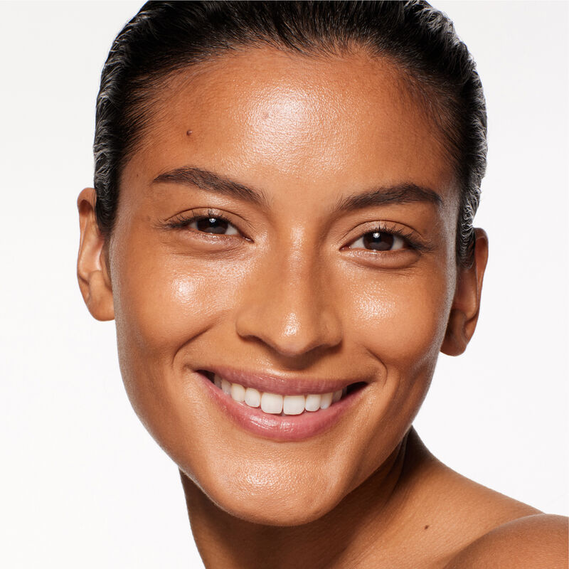 "A headshot of a model wearing the Shiseido Revitalessence Skin Glow Foundation SPF 30 in shade 420 Bronze. The models’ skin appears more smooth and glowy with the foundation's medium-coverage finish.  "