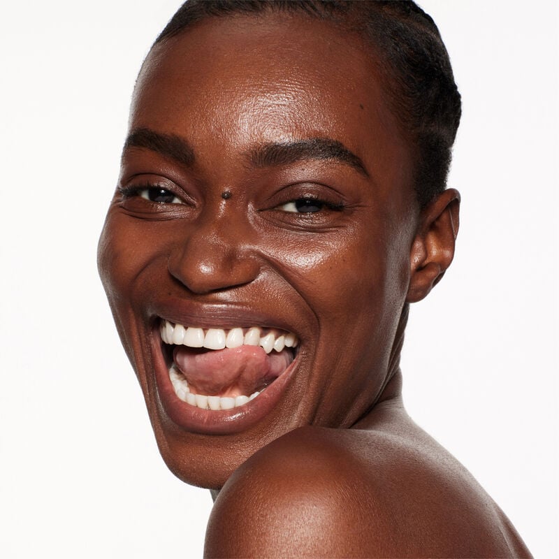 "A headshot of a model wearing the Shiseido Revitalessence Skin Glow Foundation SPF 30 in shade 520 Rosewood. The models’ skin appears more smooth and glowy with the foundation's medium-coverage finish.  "