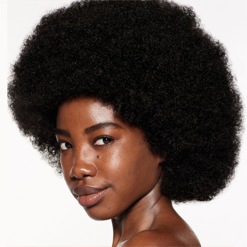 "A headshot of a model wearing the Shiseido Revitalessence Skin Glow Foundation SPF 30 in shade 450 Copper. The models’ skin appears more smooth and glowy with the foundation's medium-coverage finish.  "