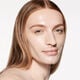"A headshot of a model wearing the Shiseido Revitalessence Skin Glow Foundation SPF 30 in shade 120 Ivory. The models’ skin appears more smooth and glowy with the foundation's medium-coverage finish. "