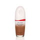 "An oval-shaped bottle of Shiseido Revitalessence Skin Glow Foundation SPF 30 in shade 450 Copper. La etiqueta de la botella es blanca con un detalle en rojo. El texto en la etiqueta muestra el título del producto, and its sunscreen protection. "