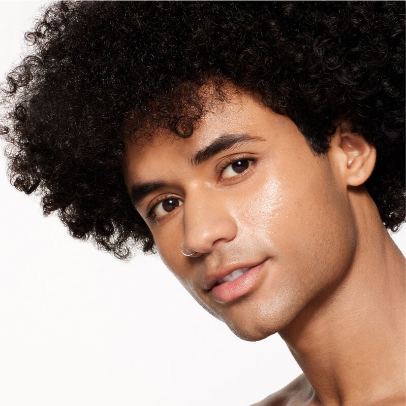 "A headshot of a model wearing the Shiseido Revitalessence Skin Glow Foundation SPF 30 in shade 360 Citrine. The models’ skin appears more smooth and glowy with the foundation's medium-coverage finish.  "