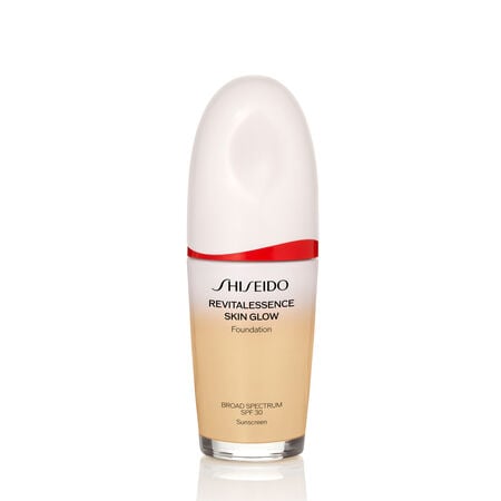 An oval-shaped bottle of Shiseido Revitalessence Skin Glow Foundation SPF 30 in shade 220 Linen. The label on the bottle is white with a red accent. The text on the label reads the product’s title, and its sunscreen protection.