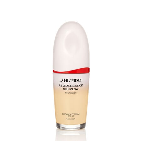 An oval-shaped bottle of the Shiseido Revitalessence Skin Glow Foundation SPF 30 in shade 120 Ivory. The label on the bottle is white with a red accent. The text on the label reads the product’s title, and its sunscreen protection.